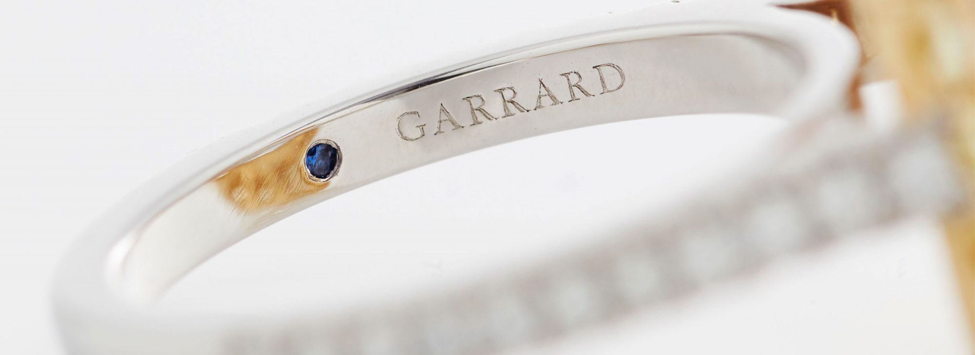 Close up of a Garrard engagement ring with a sapphire indide the diamond band