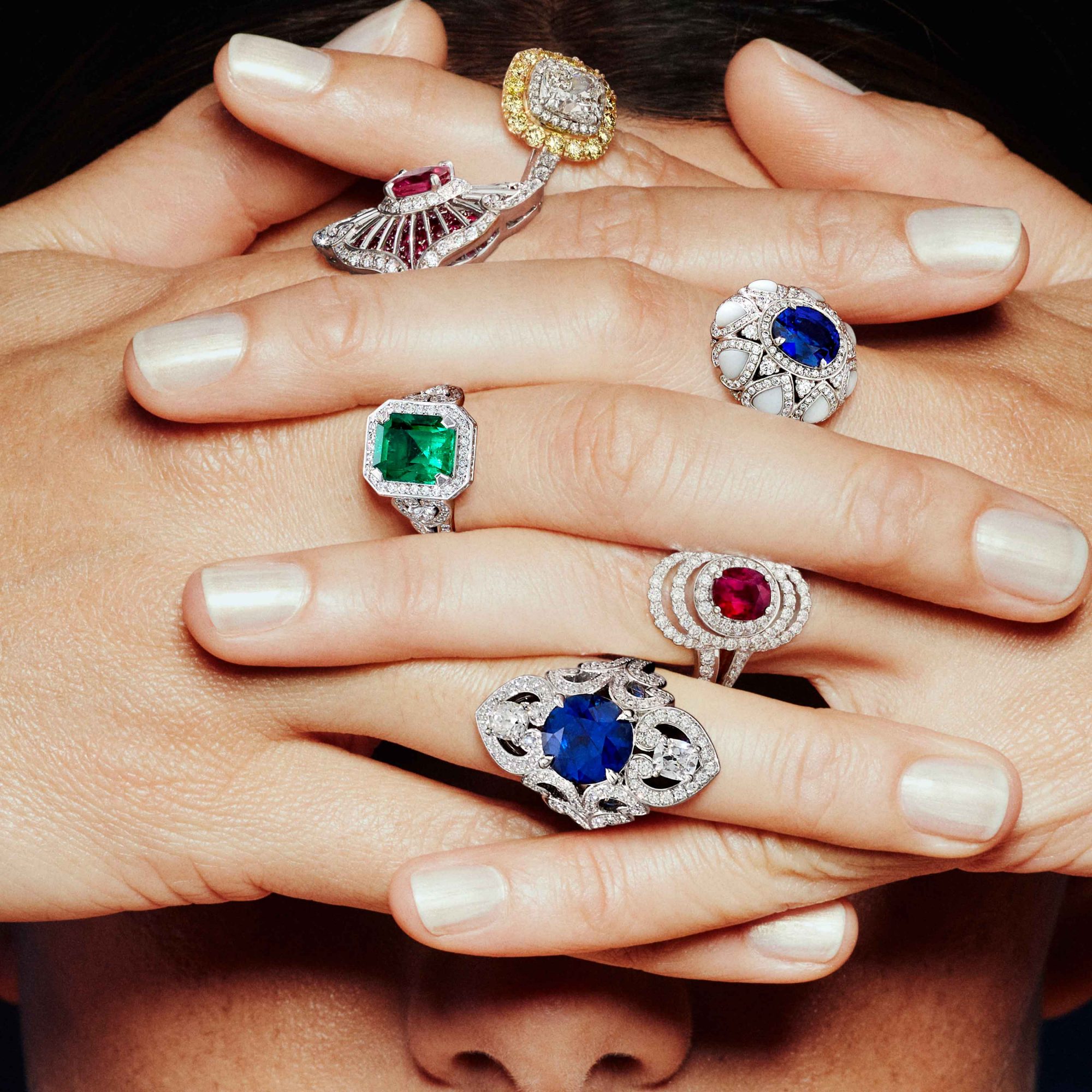 Close up of a model wearing diamond rings set with coloured gemstones each as sapphire ruby emerald 1x1 1