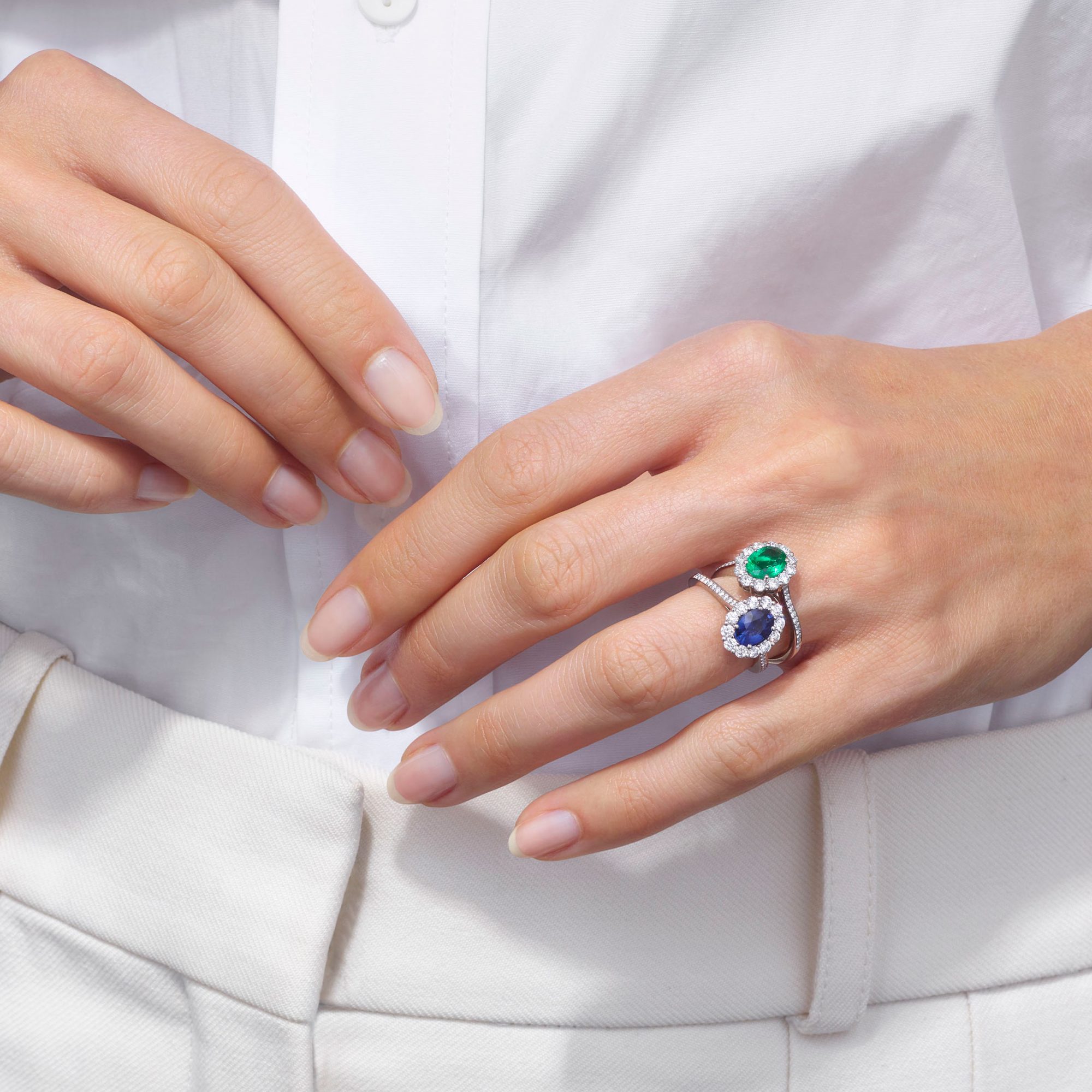 a woman wearing a stacked Garrard sapphire 1735 ring and an emerald 1735 ring on her left wedding finger square 1