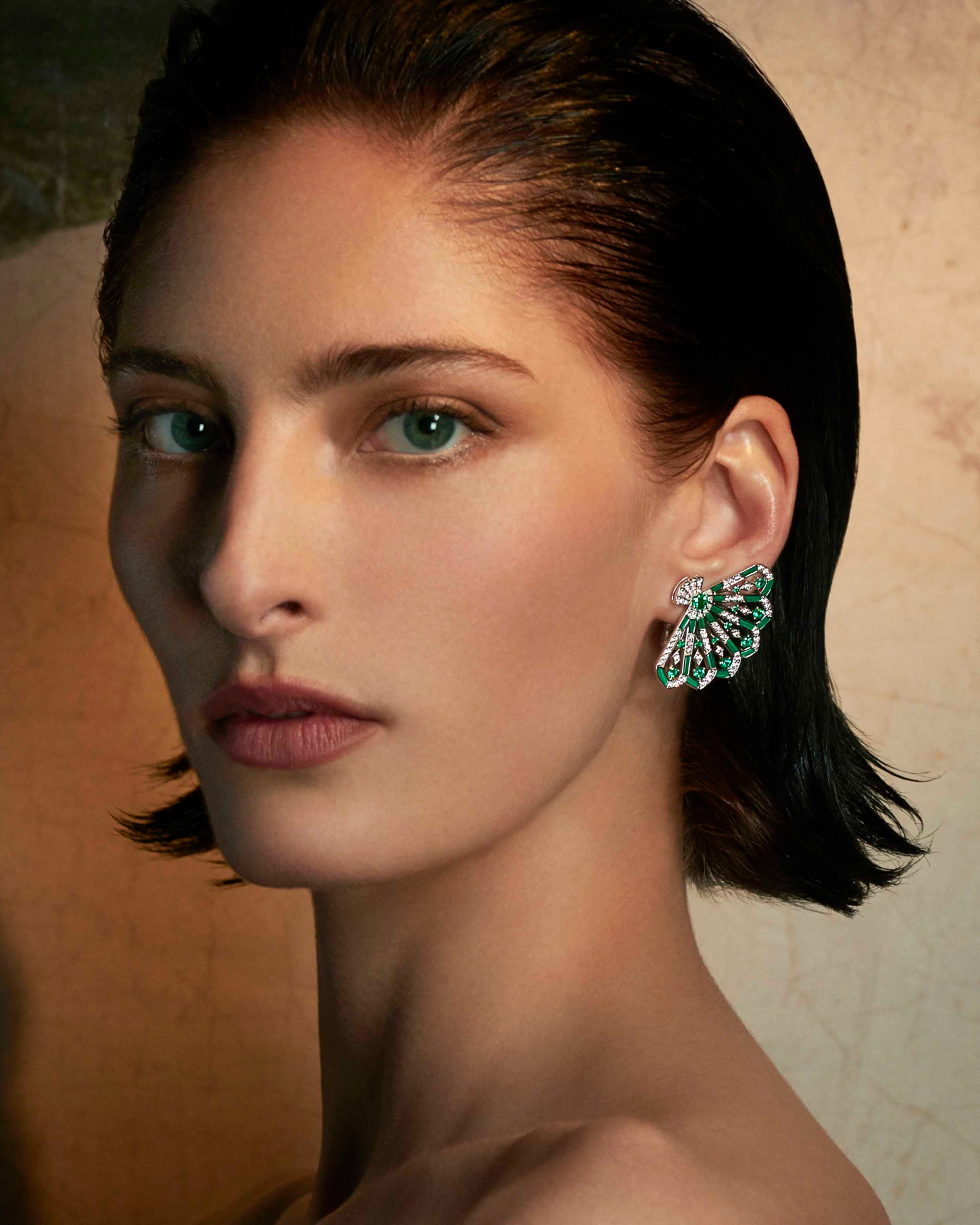 Close up of a model wearing the Garrard Fanfare Symphony jewellery collection emerald and diamond earrings 1