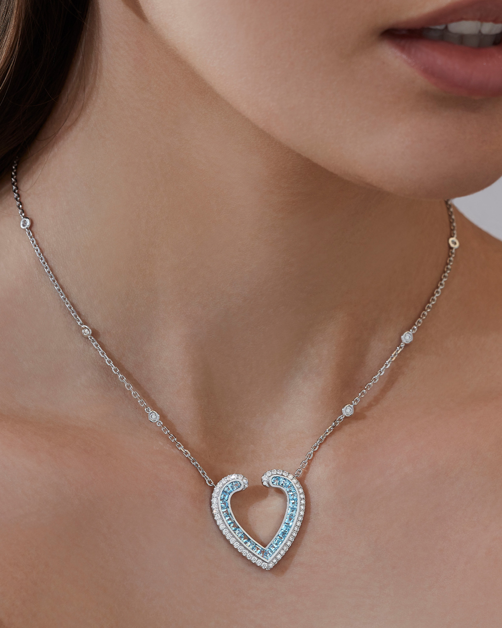 Close up of a Garrad Aloria collection aquamarine and diamond pendant on a model