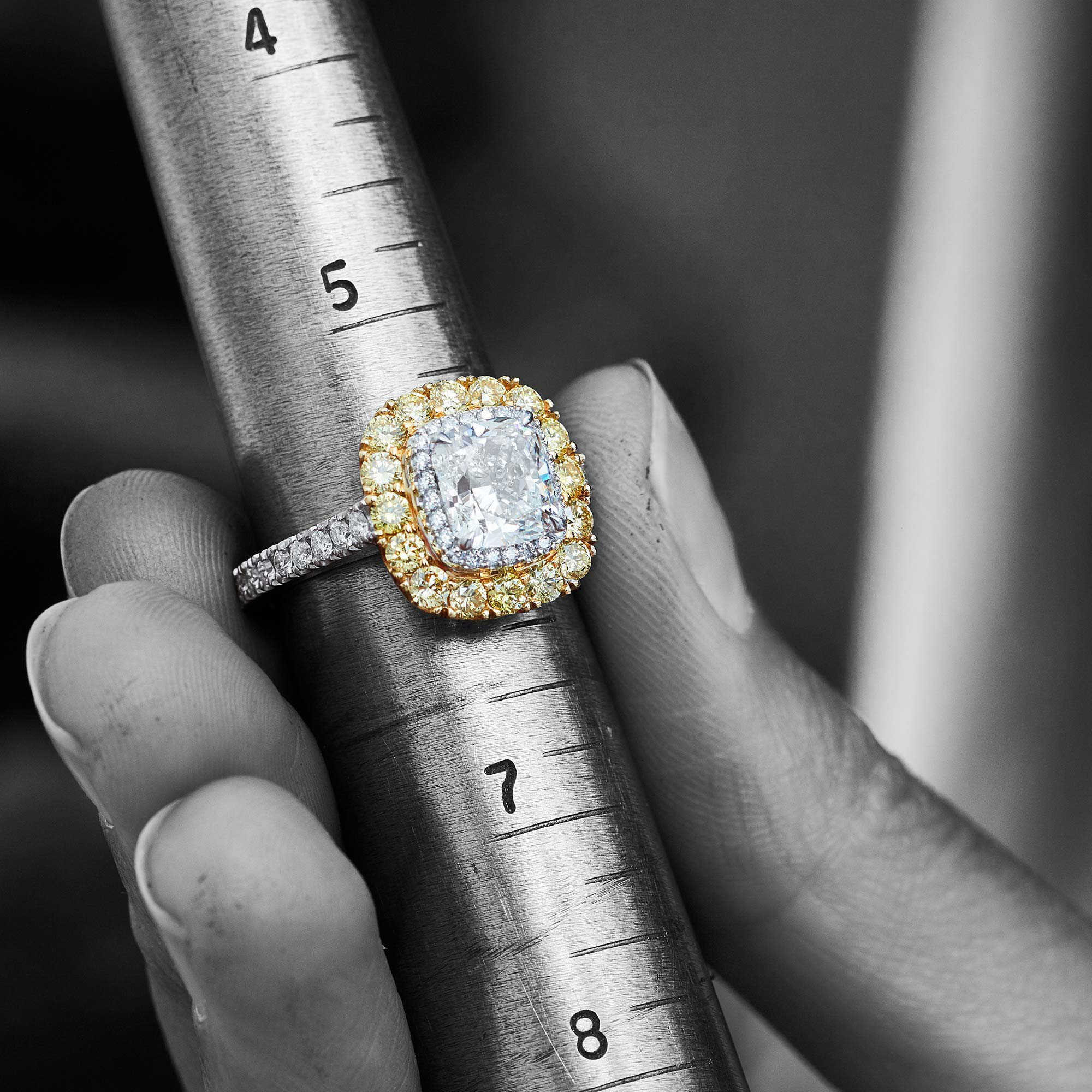 a white and yellow Garrard engagement ring resting on a finger sizer square