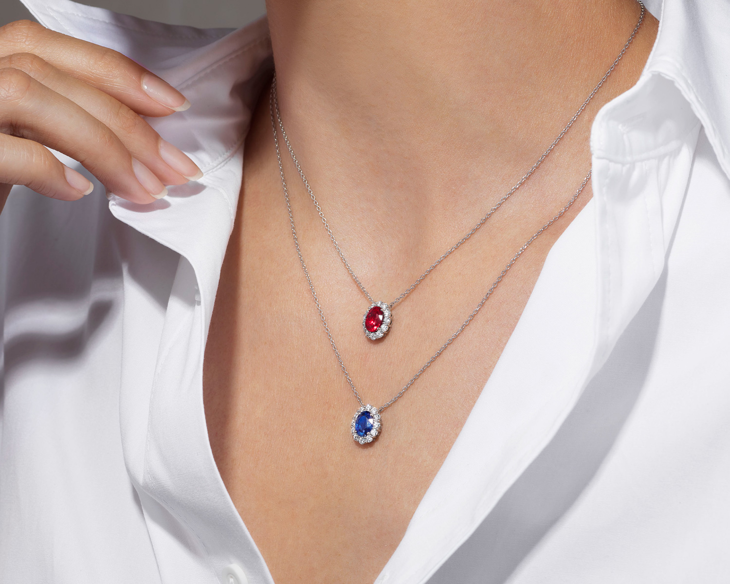 a woman wearing the Garrard 1735 jewellery collection ruby and diamond pendant and sapphire and diamond pendant